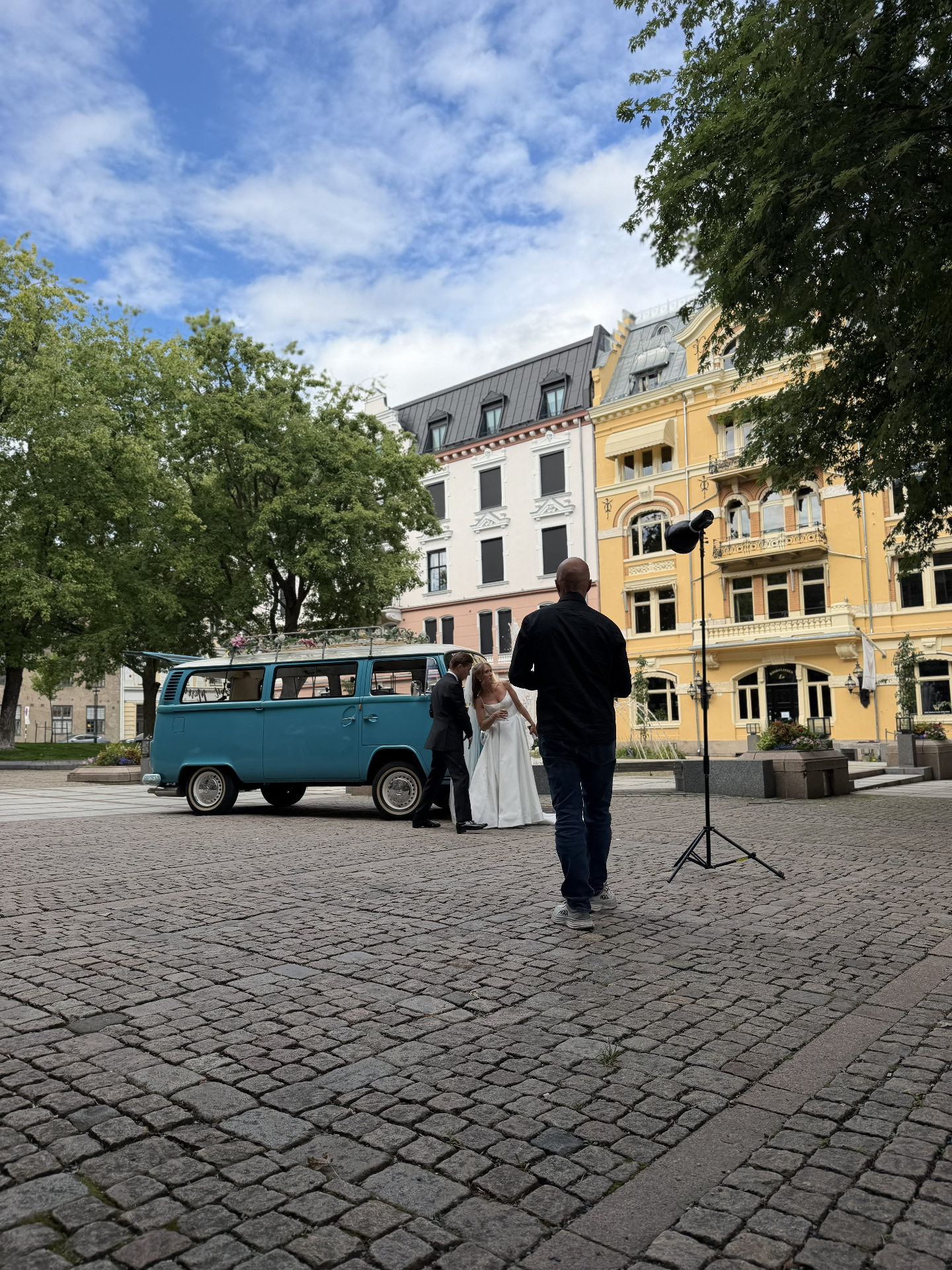 Fotograf med studiolys fotograferer brudeparet ved den turkise VW-bussen på Bankplassen i Oslo