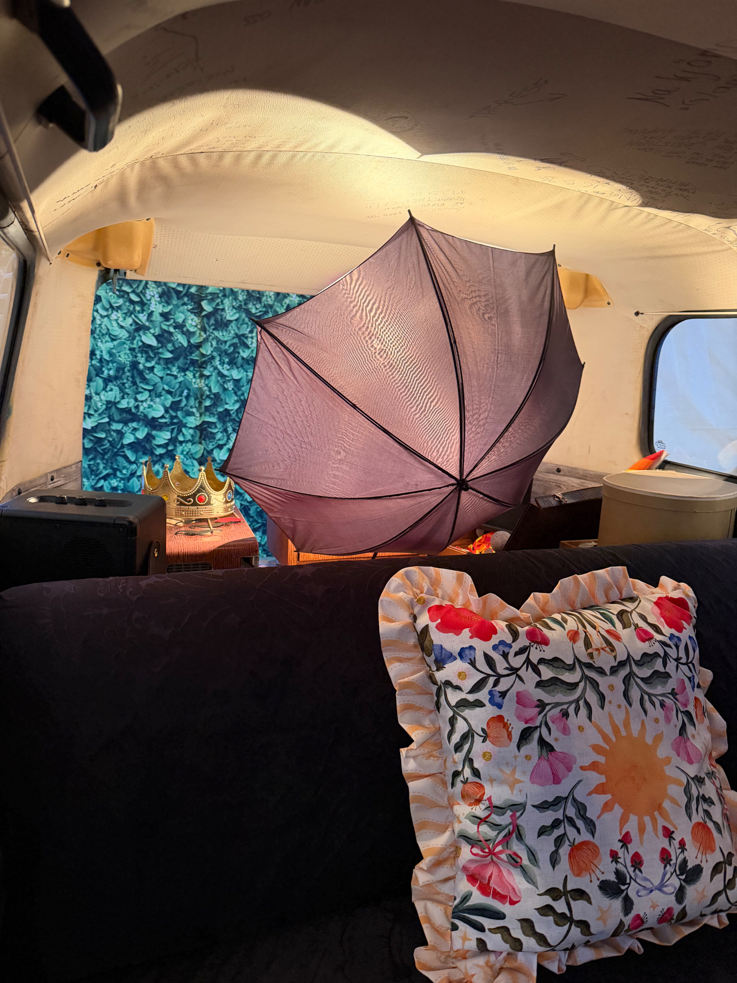 Interiør i HappySmiles photobooth-buss med blomstrete puter, paraply og håndskrevne hilsener i taket