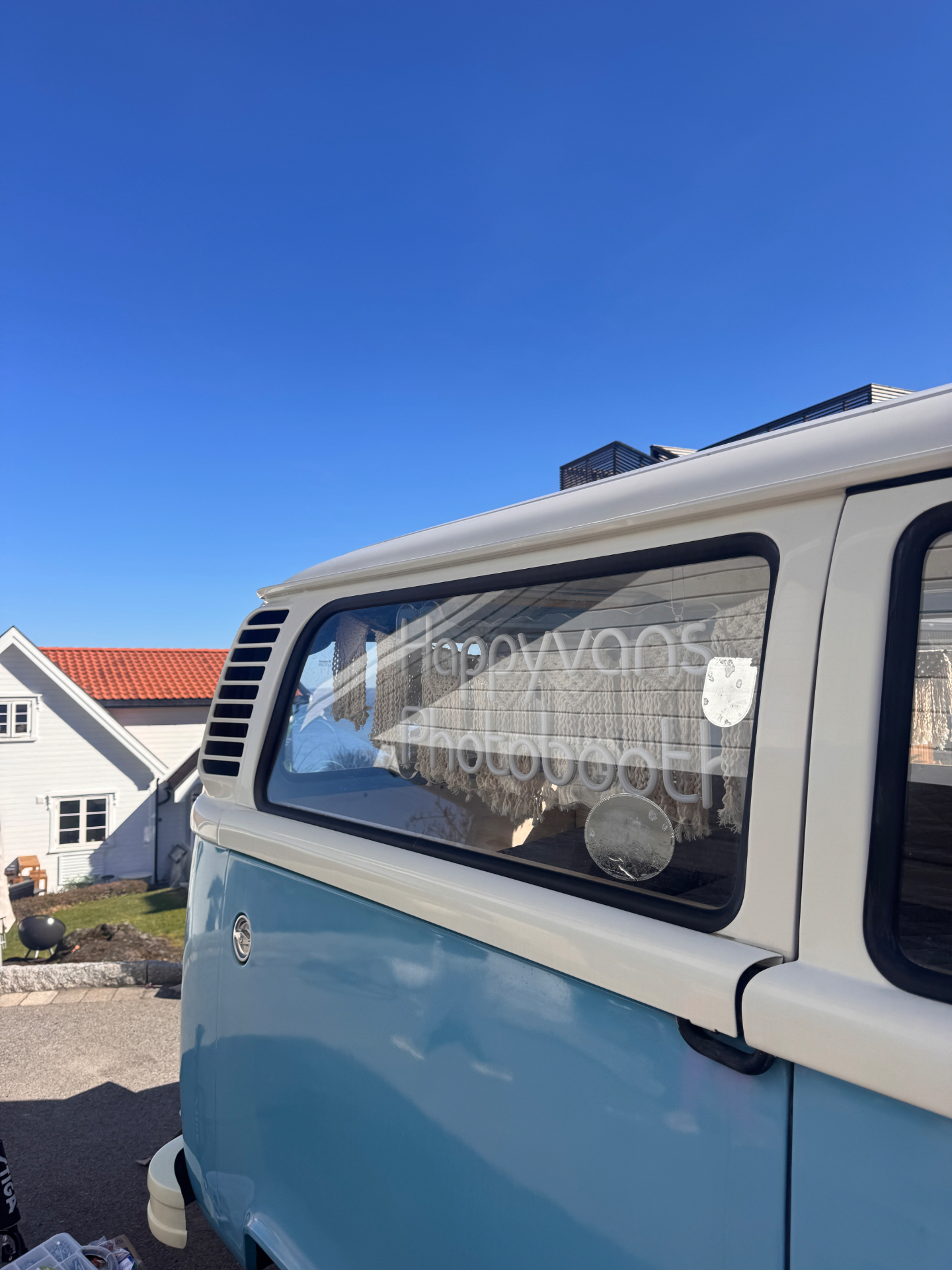 Nærbilde av lyseblå VW-buss med Happyvans Photobooth-tekst på ruta mot blå himmel