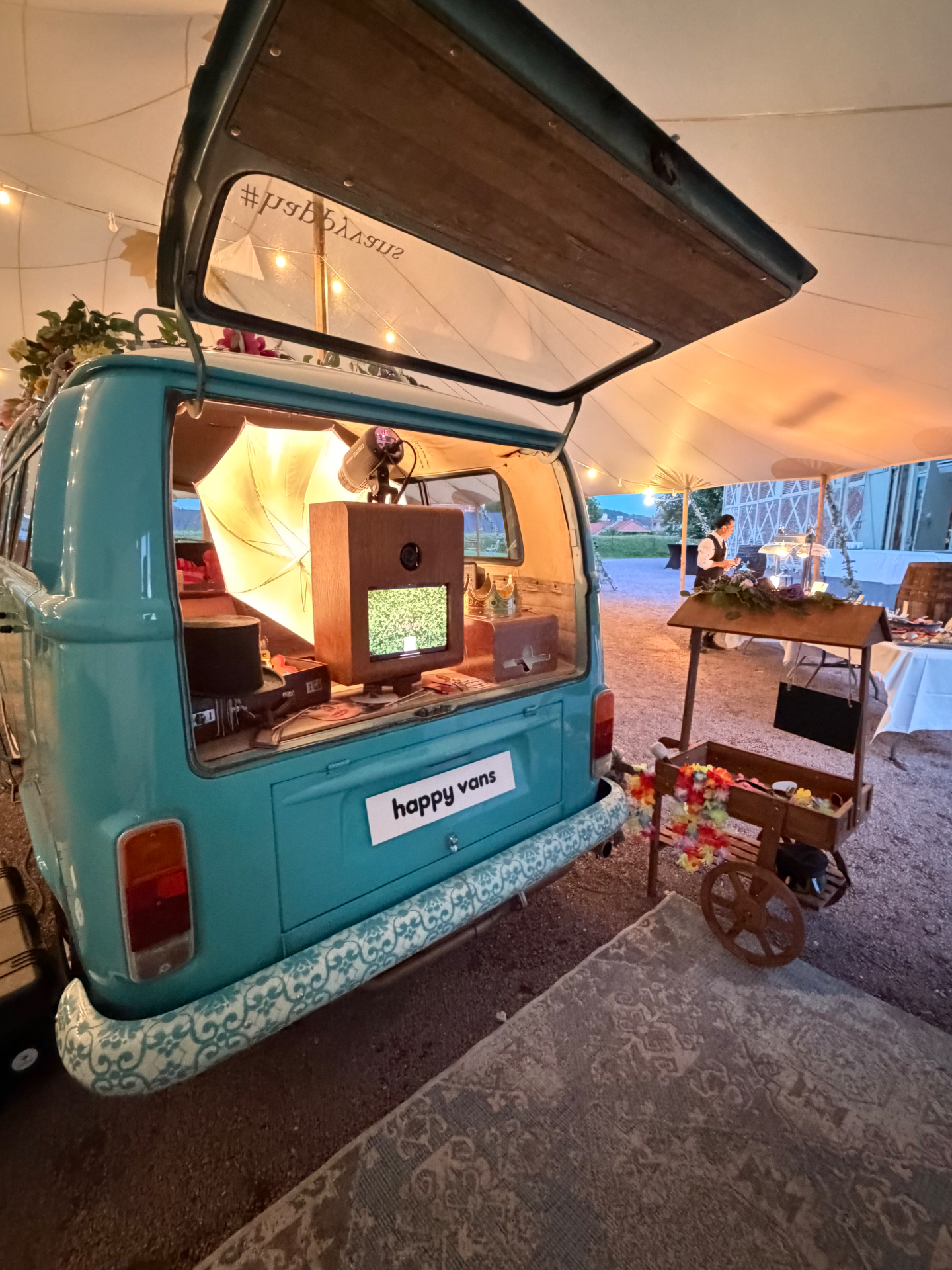 HappySmiles photobooth i bakluken på VW-bussen med varm belysning i kveldslyset, inne i teltet på Høymagasinet