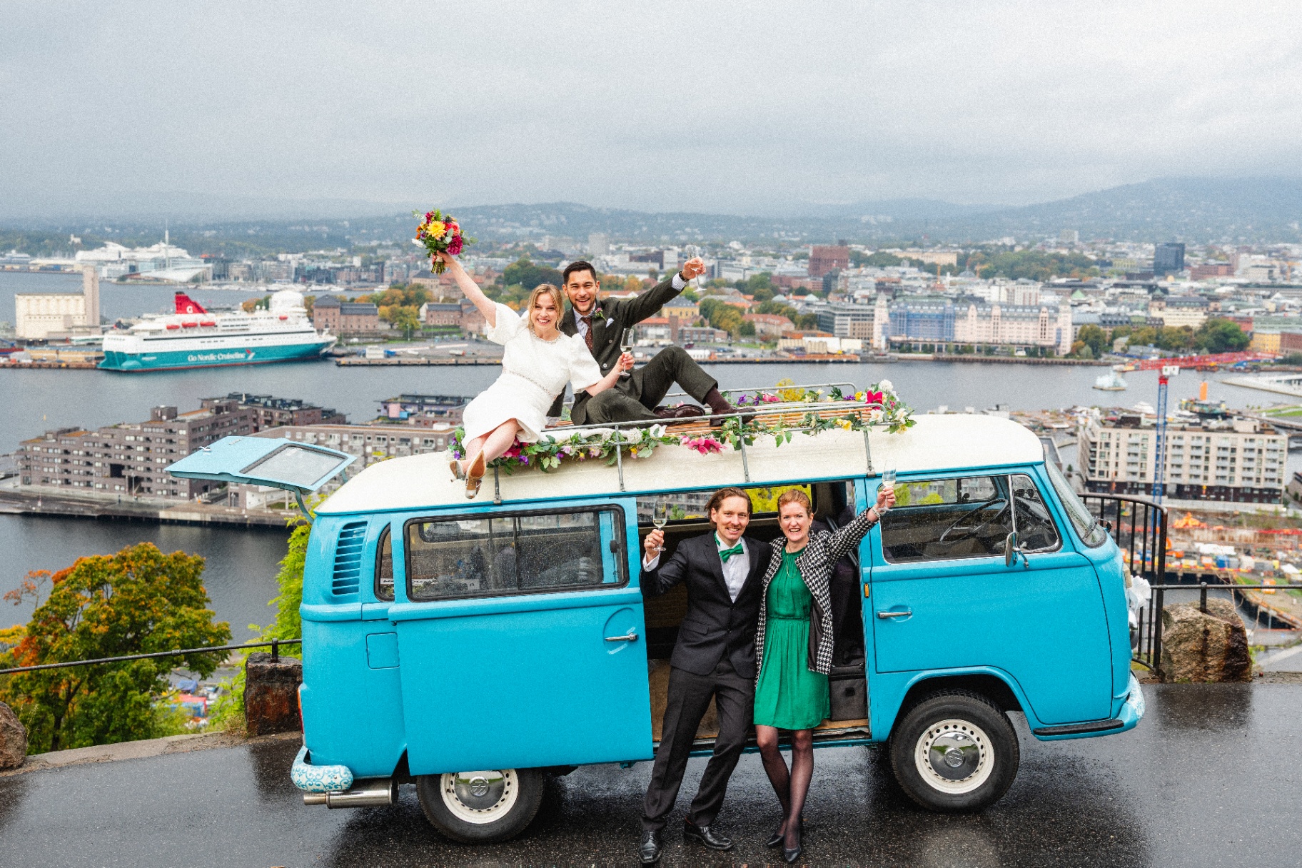 Brudepar på taket av en blå VW-buss med utsikt over Oslo havn